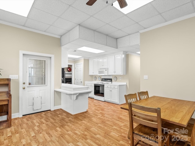 kitchen with kitchen peninsula, a breakfast bar, white appliances, light hardwood / wood-style floors, and white cabinetry