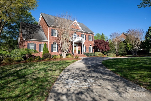 colonial house with a balcony and a front lawn