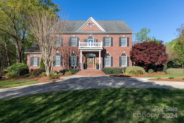 colonial home with a balcony and a front lawn