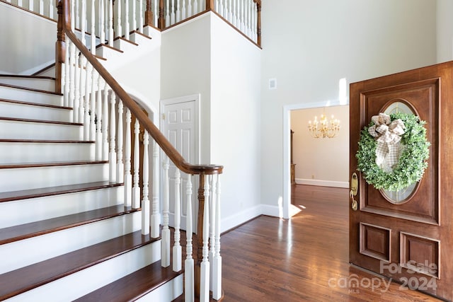 entrance foyer featuring a towering ceiling, dark hardwood / wood-style floors, and a notable chandelier