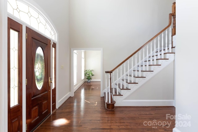 entrance foyer with dark hardwood / wood-style floors and a towering ceiling