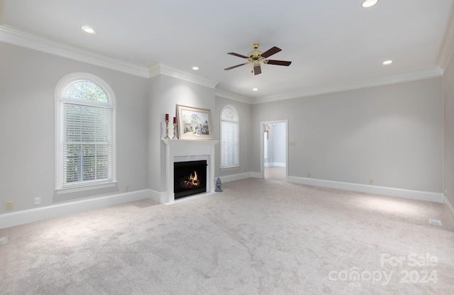 unfurnished living room featuring ceiling fan, light colored carpet, and ornamental molding