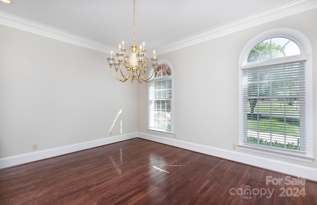 empty room featuring hardwood / wood-style floors, ornamental molding, and a chandelier