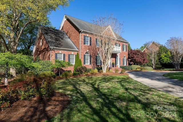 colonial-style house featuring a front lawn