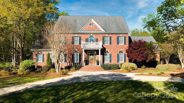 colonial house with a front yard and a balcony