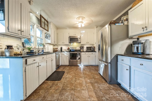 kitchen featuring stainless steel appliances, ornamental molding, sink, white cabinetry, and a textured ceiling