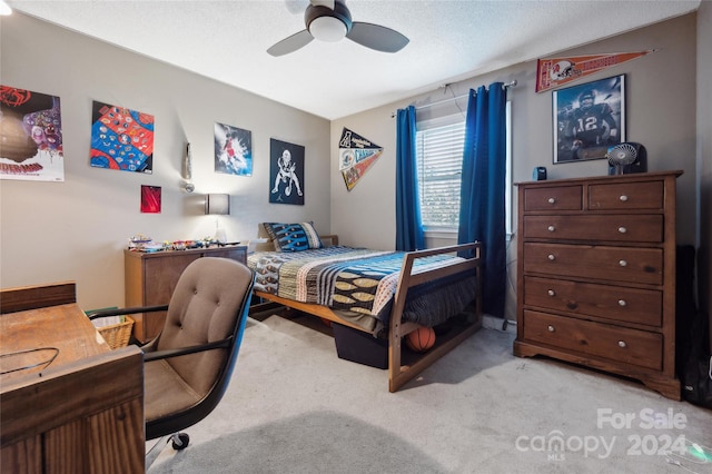 carpeted bedroom with ceiling fan and a textured ceiling