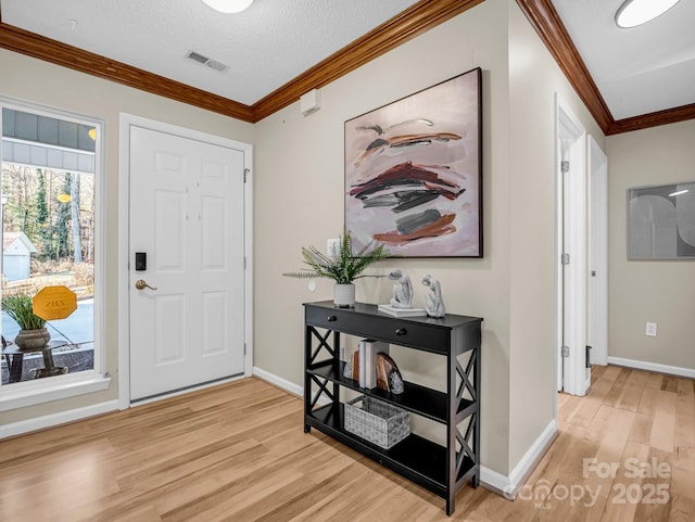 entryway with crown molding, light hardwood / wood-style flooring, and a textured ceiling