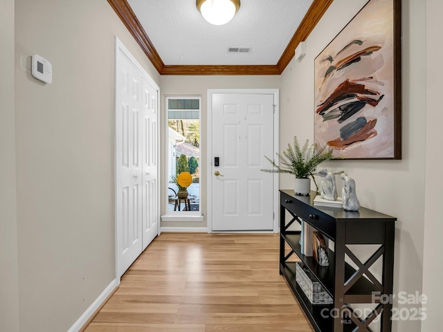 entryway featuring ornamental molding, a textured ceiling, and light hardwood / wood-style flooring