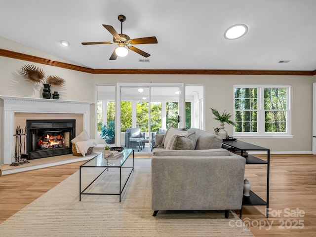 living room featuring crown molding, light hardwood / wood-style flooring, ceiling fan, and vaulted ceiling