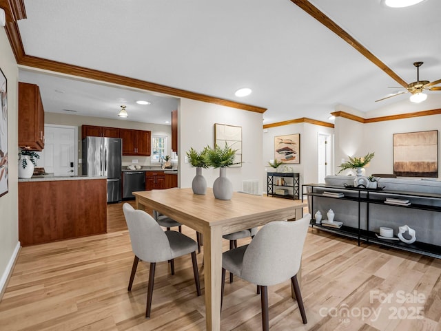 dining area featuring ornamental molding, vaulted ceiling, ceiling fan, and light hardwood / wood-style flooring