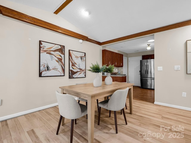 dining room with vaulted ceiling and light hardwood / wood-style floors