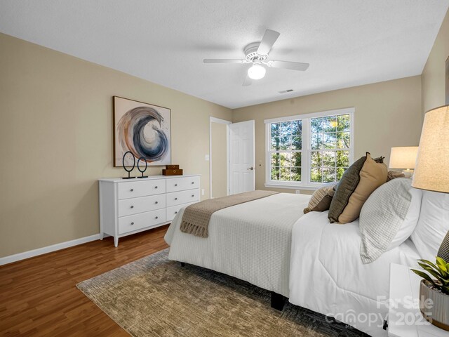 bedroom with ceiling fan, dark hardwood / wood-style flooring, and a textured ceiling