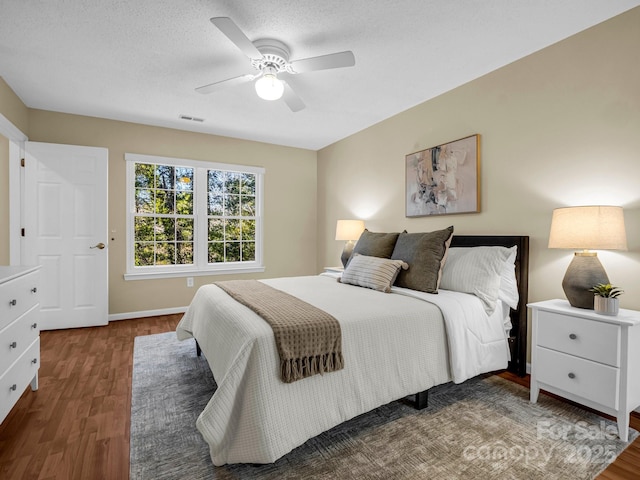 bedroom with ceiling fan, dark hardwood / wood-style flooring, and a textured ceiling