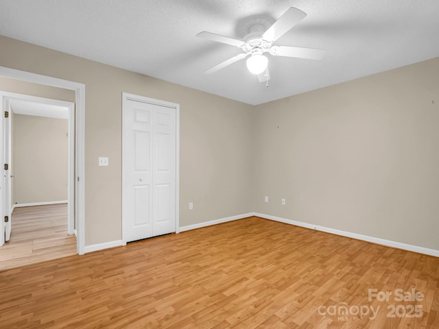 unfurnished bedroom with ceiling fan, light hardwood / wood-style flooring, a closet, and a textured ceiling