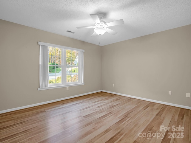 spare room featuring ceiling fan, light hardwood / wood-style flooring, and a textured ceiling