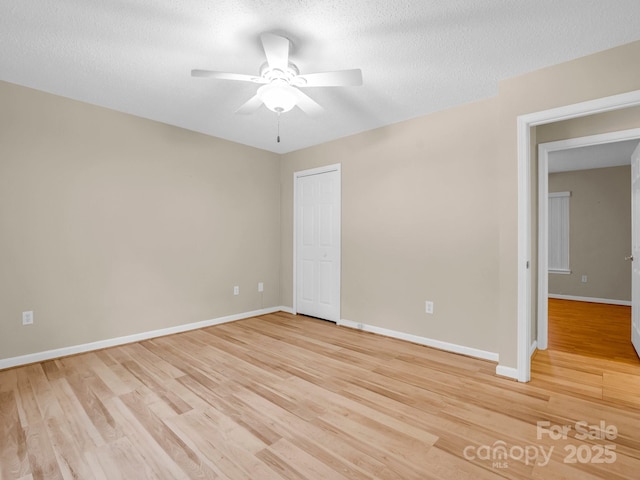 empty room featuring a textured ceiling, light hardwood / wood-style flooring, and ceiling fan