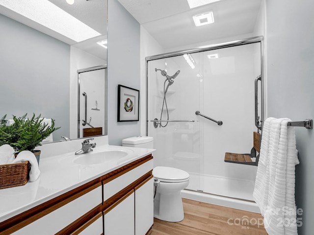 bathroom featuring walk in shower, toilet, a skylight, vanity, and hardwood / wood-style floors