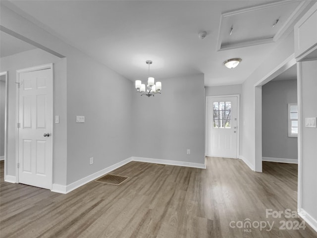 spare room featuring an inviting chandelier and hardwood / wood-style floors