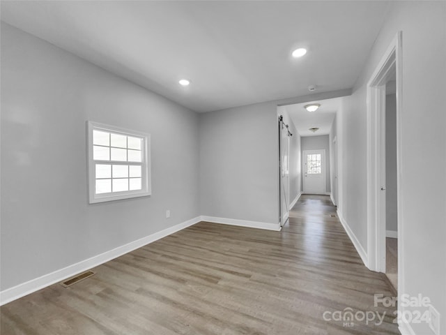 unfurnished room featuring light hardwood / wood-style flooring, a wealth of natural light, and a barn door