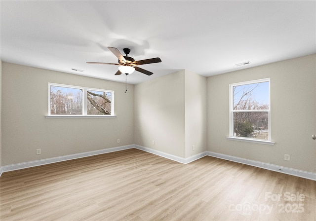 spare room with light wood finished floors, visible vents, and baseboards