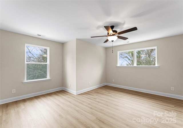 spare room featuring a wealth of natural light, baseboards, visible vents, and light wood finished floors