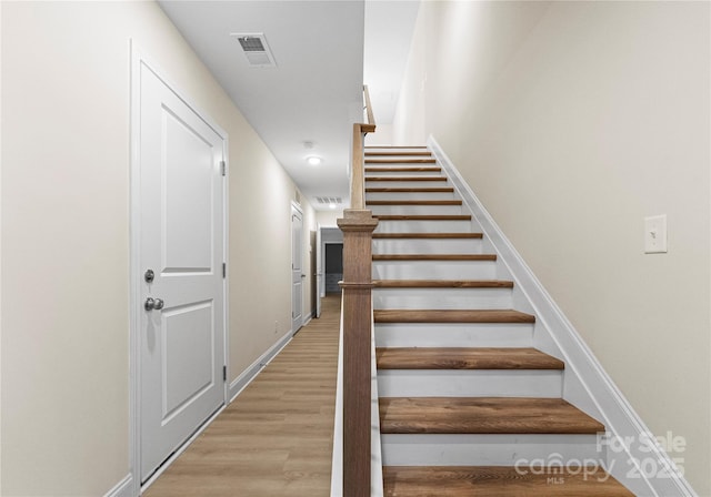 stairway with baseboards, visible vents, and wood finished floors