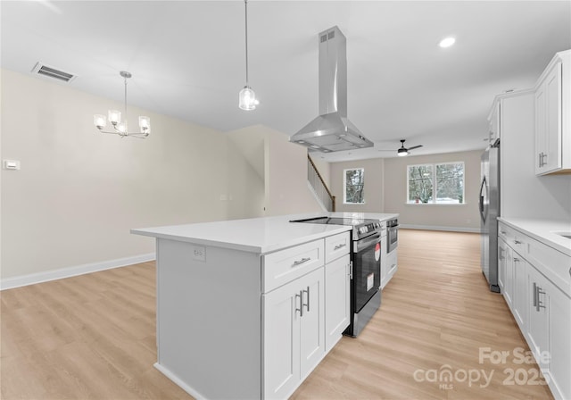 kitchen with island range hood, white cabinets, appliances with stainless steel finishes, open floor plan, and light countertops