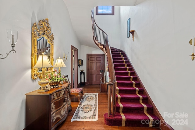 interior space with a towering ceiling and hardwood / wood-style flooring