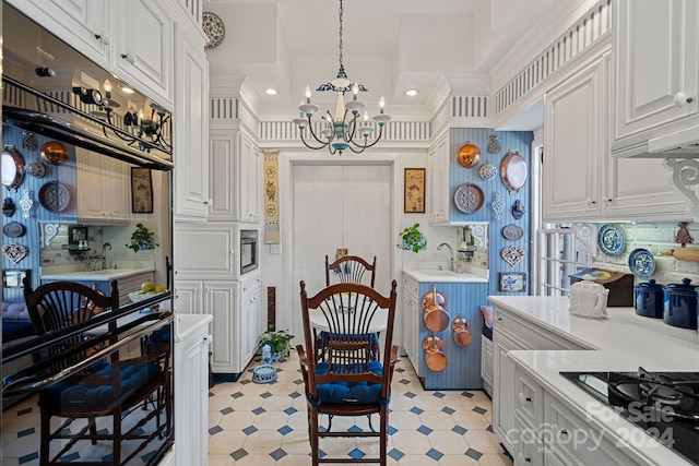 kitchen featuring black appliances, white cabinets, a chandelier, and a kitchen breakfast bar