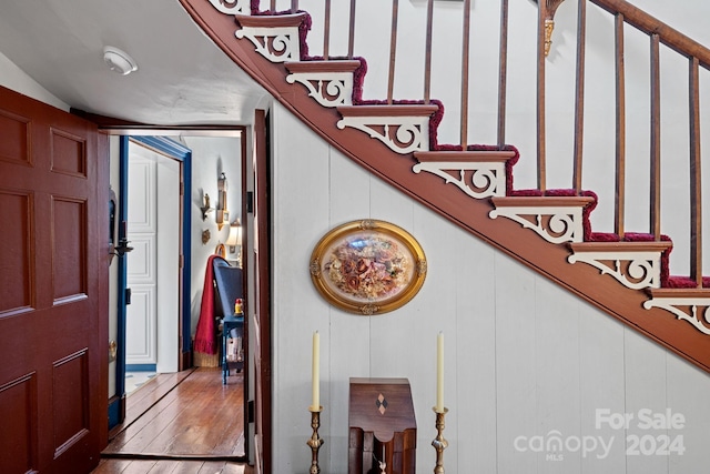 stairs featuring wood-type flooring and wooden walls