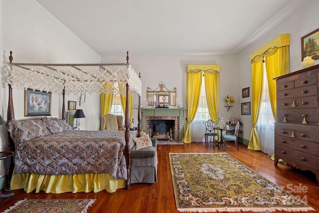 bedroom with wood-type flooring and a brick fireplace