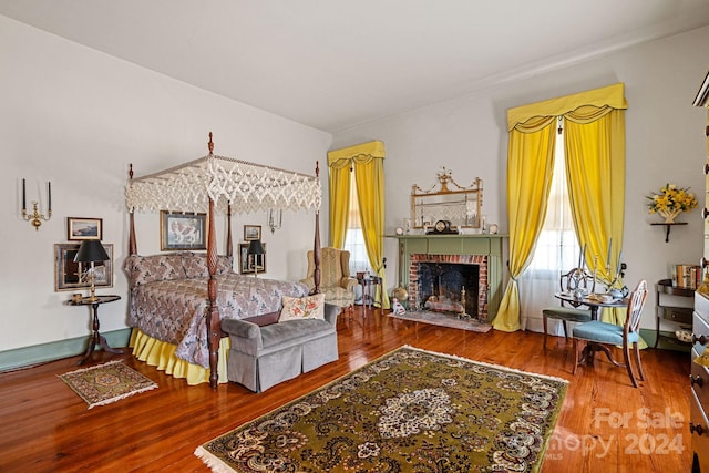 bedroom featuring hardwood / wood-style floors and a brick fireplace