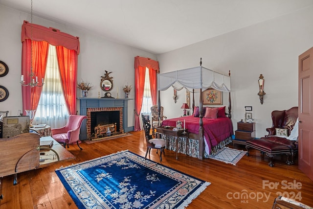 bedroom with hardwood / wood-style floors and a brick fireplace