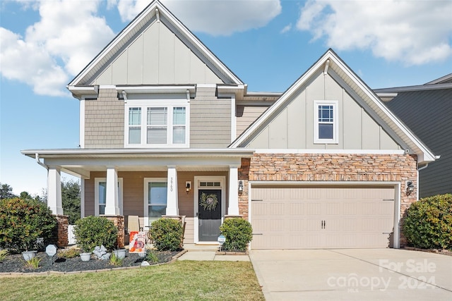 craftsman-style home featuring a front yard, a garage, and covered porch