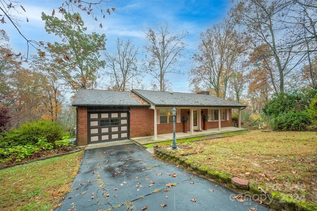 view of front facade featuring a garage, a front yard, and covered porch