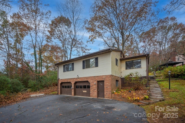 view of front of house featuring aphalt driveway, brick siding, and a garage