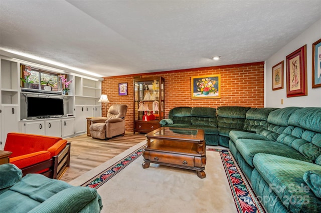 living area featuring brick wall, a textured ceiling, and wood finished floors