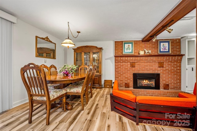 dining area with a fireplace, wood finished floors, beam ceiling, and baseboards