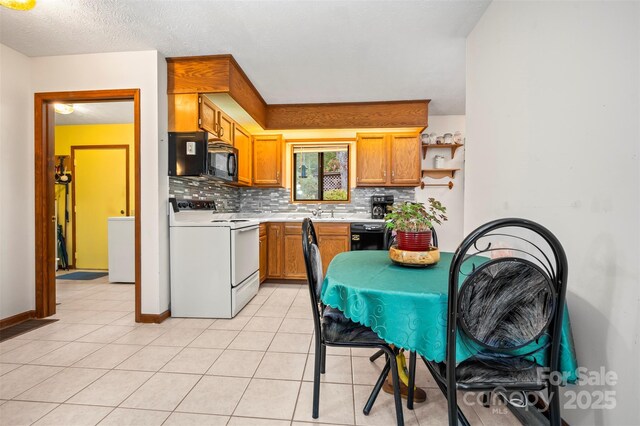 kitchen featuring brown cabinets, light tile patterned floors, light countertops, backsplash, and black appliances