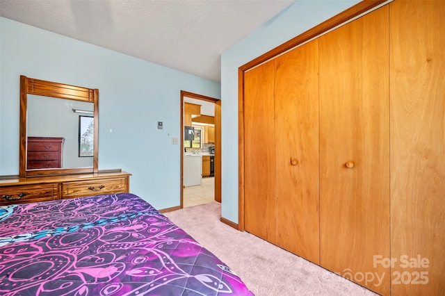 bedroom featuring light carpet, washer / dryer, a closet, and a textured ceiling