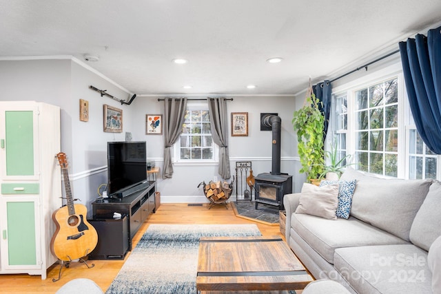 living room featuring light hardwood / wood-style flooring, a wood stove, and ornamental molding