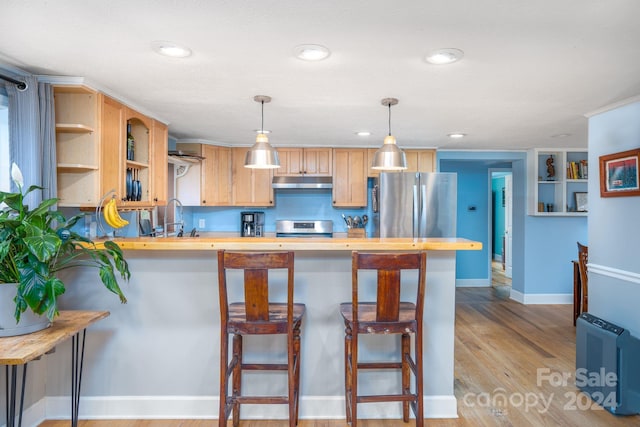 kitchen featuring a kitchen breakfast bar, hanging light fixtures, stainless steel appliances, and kitchen peninsula