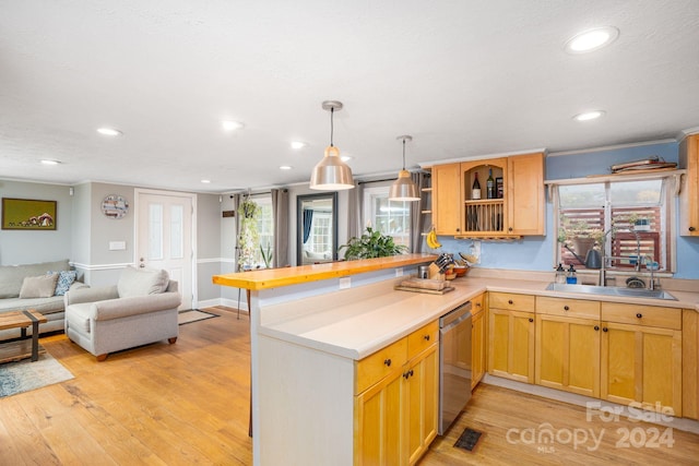 kitchen with kitchen peninsula, sink, decorative light fixtures, light wood-type flooring, and stainless steel dishwasher