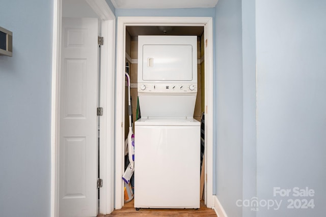 laundry area with light hardwood / wood-style floors and stacked washing maching and dryer