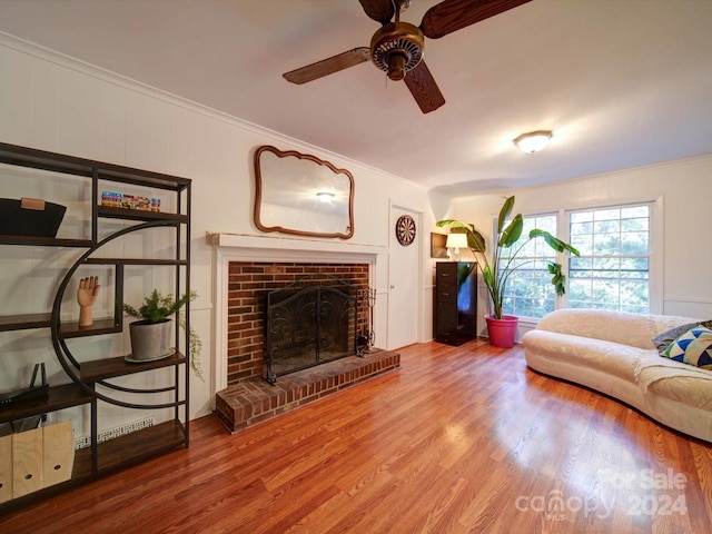 living room featuring a fireplace, wood-type flooring, ceiling fan, and crown molding