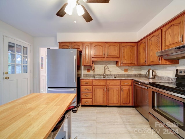 kitchen featuring ventilation hood, appliances with stainless steel finishes, decorative backsplash, sink, and ceiling fan