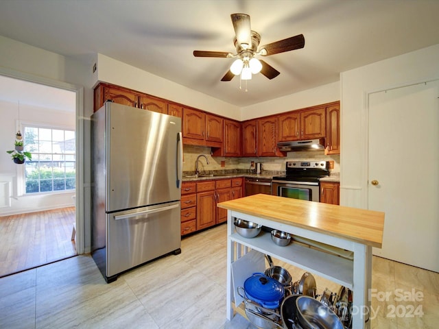 kitchen featuring tasteful backsplash, stainless steel appliances, sink, ceiling fan, and light hardwood / wood-style flooring