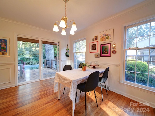 dining area featuring light wood-type flooring, plenty of natural light, a chandelier, and crown molding