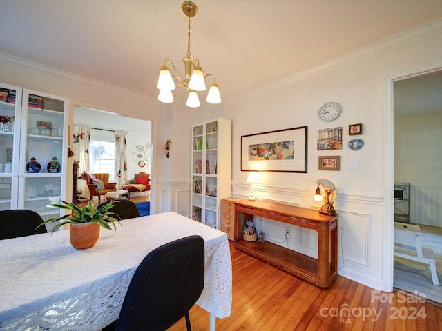 dining area featuring a notable chandelier, crown molding, and light hardwood / wood-style flooring